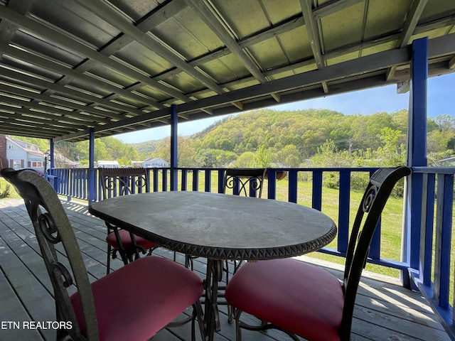 deck featuring outdoor dining area and a view of trees