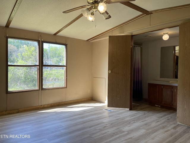 interior space featuring light wood-style floors, visible vents, vaulted ceiling with beams, and a sink