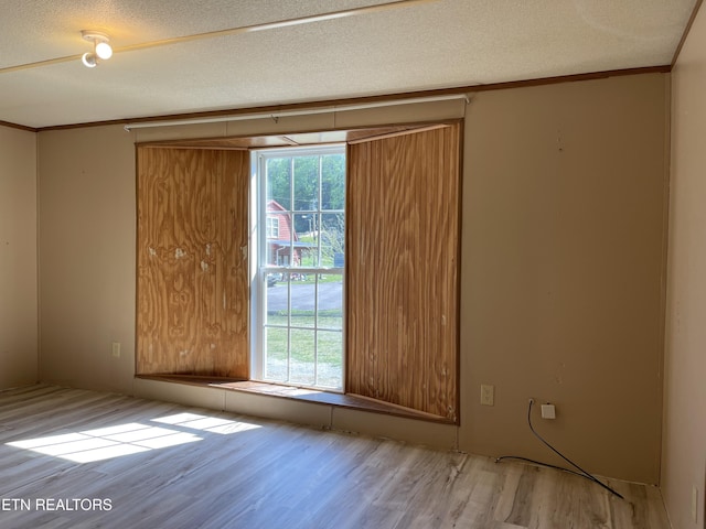 unfurnished room featuring wood finished floors, a textured ceiling, and ornamental molding