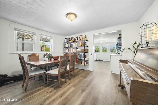 dining area with wood finished floors, a textured ceiling, and baseboards