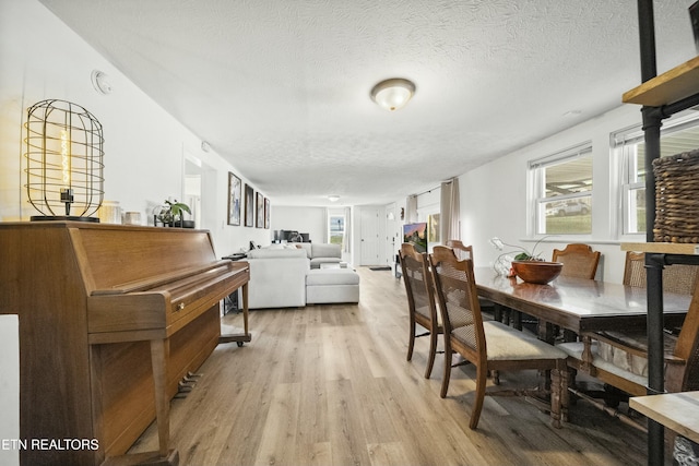 dining space with light wood finished floors and a textured ceiling