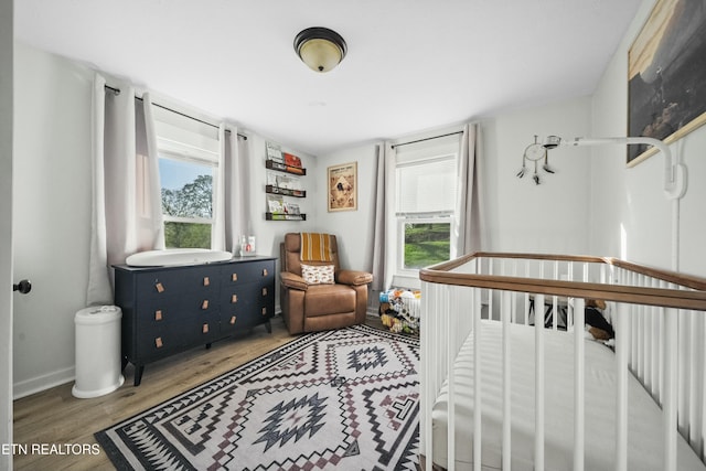 bedroom with wood finished floors and a nursery area