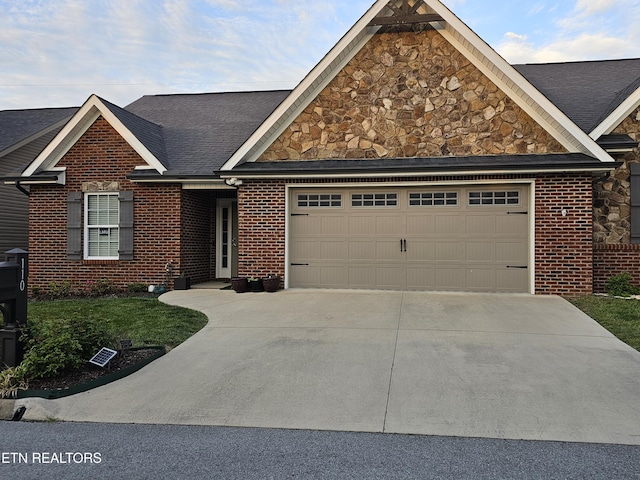 view of front facade with roof with shingles, driveway, stone siding, brick siding, and an attached garage