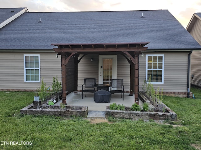 back of house with a lawn, a patio, and roof with shingles