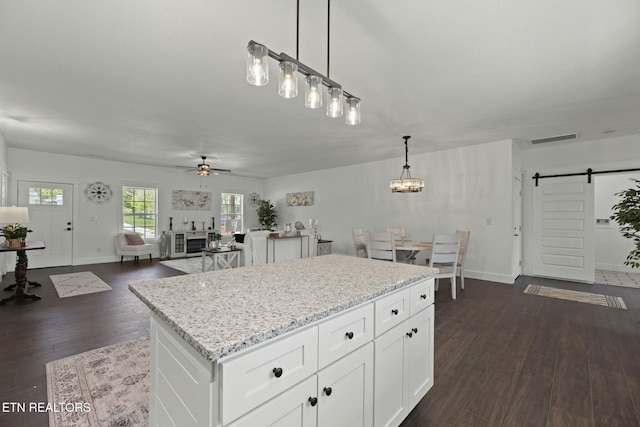 252 Old Middlesboro Hwy, Lafollette, TN 37766 - kitchen with a barn door, ceiling fan with notable chandelier, dark wood finished floors, white cabinetry, and visible vents