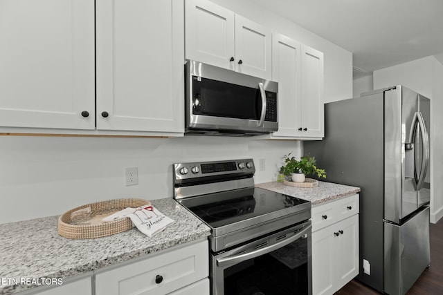 252 Old Middlesboro Hwy, Lafollette, TN 37766 - kitchen featuring appliances with stainless steel finishes, light stone countertops, dark wood-type flooring, and white cabinetry