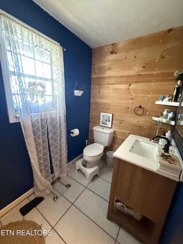 bathroom featuring tile patterned floors, wood walls, vanity, and toilet
