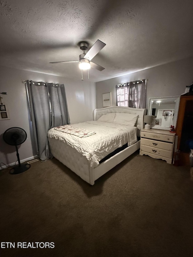 bedroom with a ceiling fan, dark carpet, and a textured ceiling