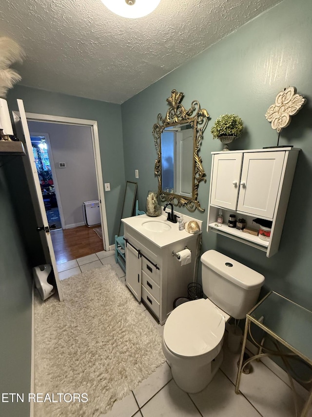 bathroom with a textured ceiling, tile patterned floors, vanity, and toilet