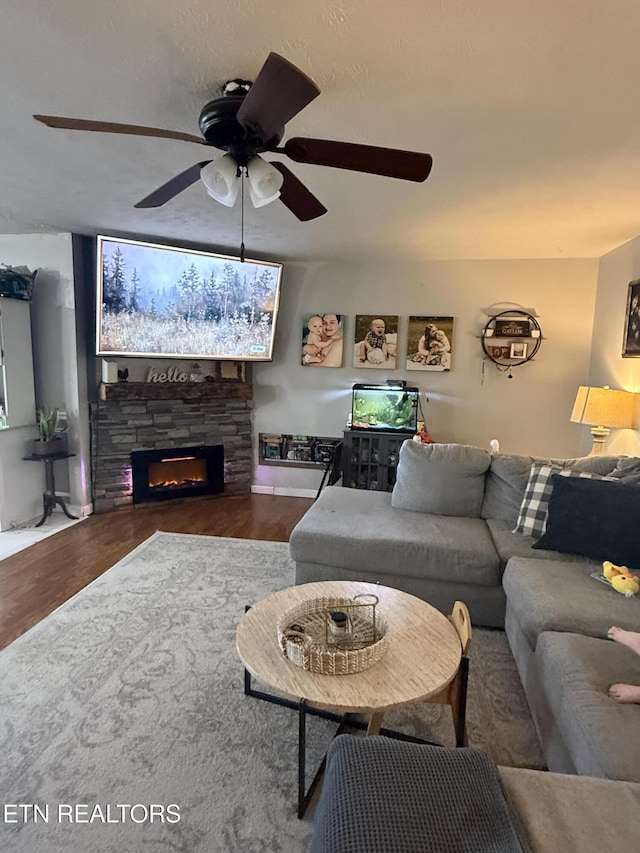 living area with a fireplace, wood finished floors, and ceiling fan