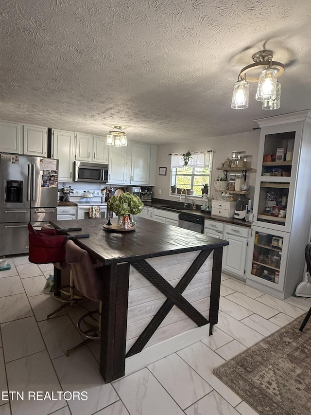 kitchen with tasteful backsplash, dark countertops, appliances with stainless steel finishes, marble finish floor, and a sink