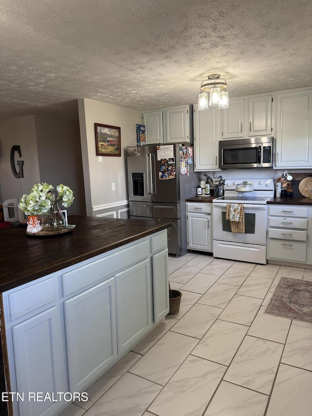 kitchen with butcher block countertops, a textured ceiling, and stainless steel appliances