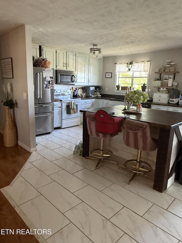 kitchen featuring a textured ceiling, appliances with stainless steel finishes, a sink, and dark countertops