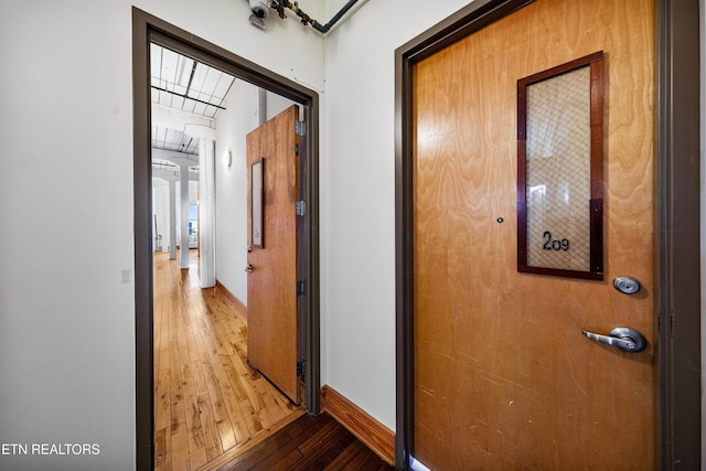hallway featuring light wood-type flooring and baseboards