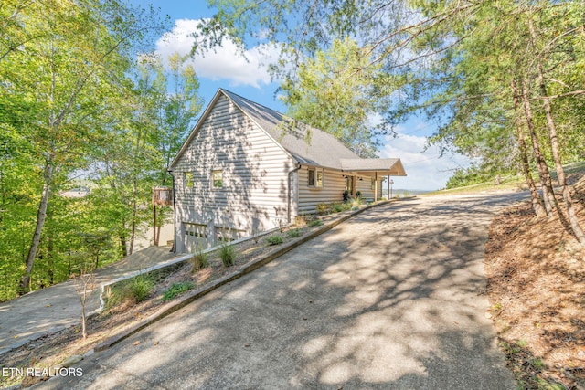 view of side of home featuring an attached garage and aphalt driveway