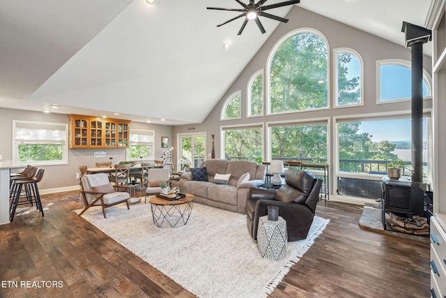 living area with dark wood-style flooring, recessed lighting, ceiling fan, high vaulted ceiling, and a wood stove