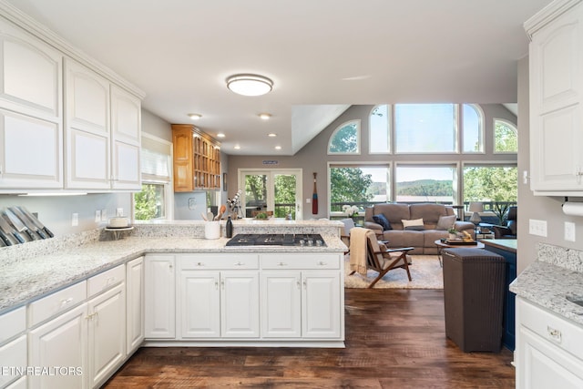 kitchen featuring white cabinets, a peninsula, stainless steel gas cooktop, dark wood-style floors, and light stone counters