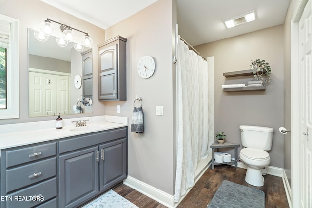 full bathroom with toilet, baseboards, visible vents, wood finished floors, and vanity