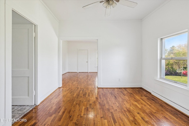 unfurnished room with a baseboard radiator, ceiling fan, wood-type flooring, baseboards, and ornamental molding