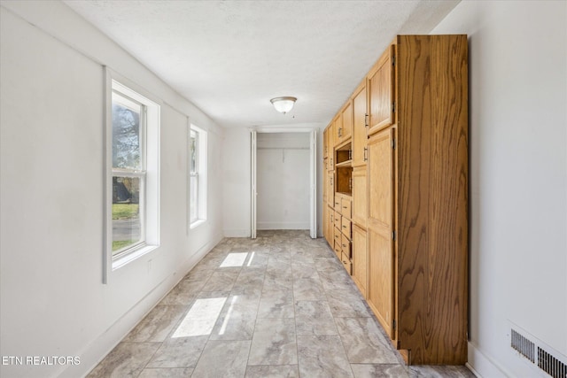 hall featuring baseboards and visible vents