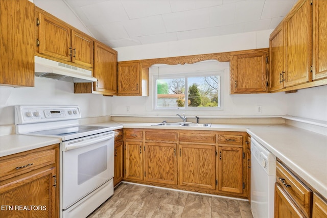 kitchen featuring brown cabinets, under cabinet range hood, a sink, and white appliances