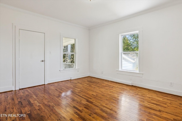 unfurnished room featuring wood-type flooring, crown molding, and baseboards