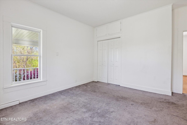 unfurnished bedroom with a baseboard radiator, baseboards, a closet, and carpet