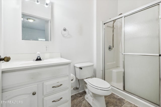 bathroom with baseboards, a shower stall, toilet, and vanity