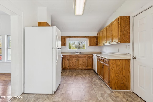 kitchen featuring a sink, baseboard heating, white appliances, brown cabinetry, and light countertops