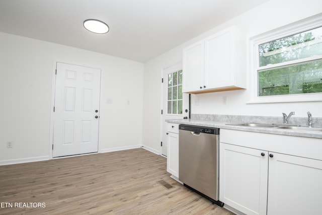 kitchen featuring stainless steel dishwasher, a sink, light wood finished floors, light countertops, and visible vents