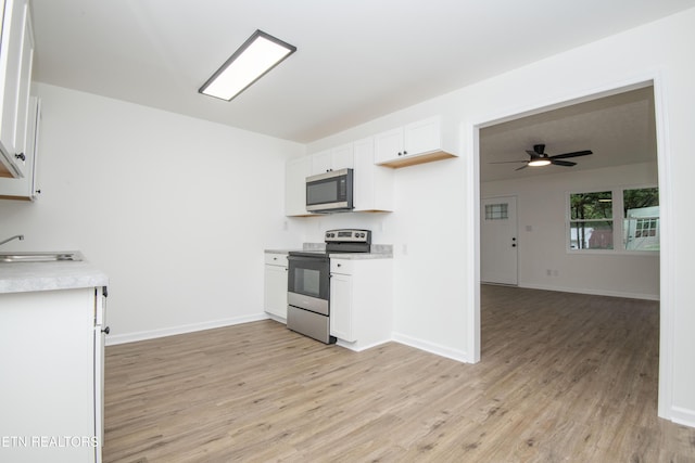 kitchen with light wood-style flooring, a sink, a ceiling fan, light countertops, and appliances with stainless steel finishes