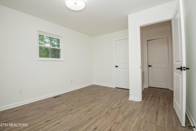 unfurnished bedroom with light wood-style flooring, visible vents, and baseboards