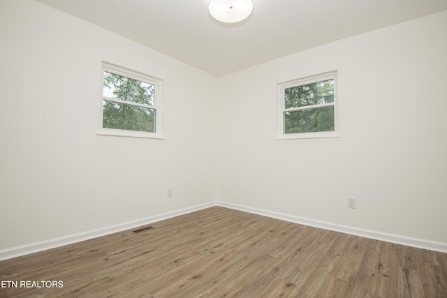 unfurnished room with baseboards, wood finished floors, and visible vents