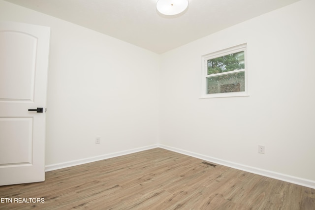 unfurnished room featuring baseboards, light wood-style flooring, and visible vents