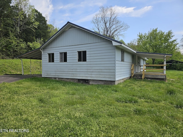 view of property exterior with a lawn, an attached carport, and aphalt driveway