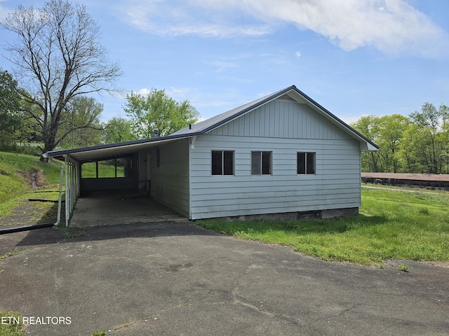 view of side of home with a lawn, aphalt driveway, and an attached carport