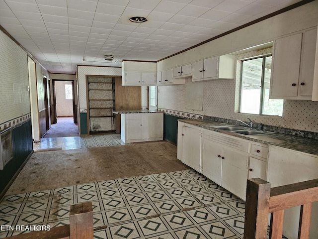 kitchen featuring dark countertops, a sink, white cabinetry, and crown molding