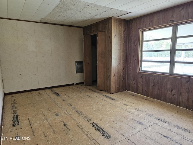 spare room featuring wooden walls, visible vents, and baseboards