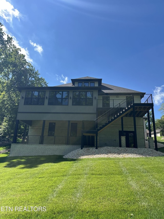 rear view of property featuring a yard, stairway, and brick siding