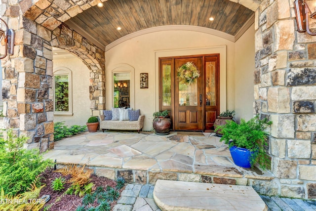 view of exterior entry featuring stone siding and stucco siding