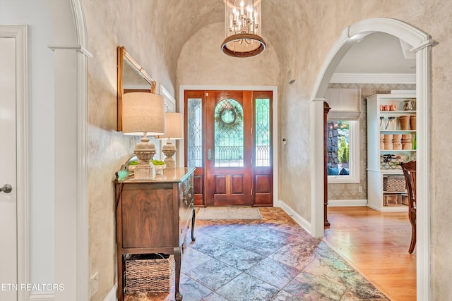entrance foyer with wood finished floors, arched walkways, baseboards, and lofted ceiling