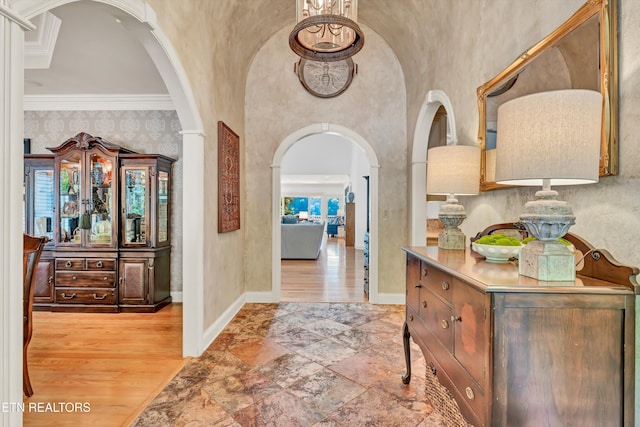 hall featuring stone tile floors, arched walkways, and baseboards