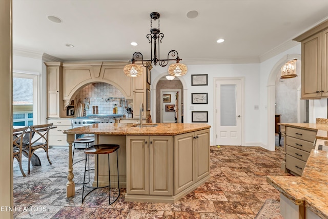 kitchen featuring a sink, arched walkways, decorative light fixtures, and cream cabinetry
