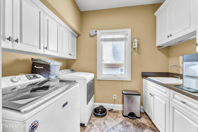 washroom featuring baseboards, a sink, cabinet space, and washer and clothes dryer