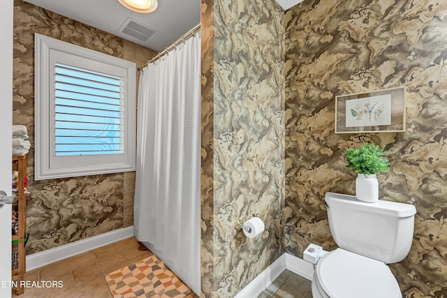 bathroom featuring a shower with curtain, visible vents, baseboards, tile patterned floors, and toilet