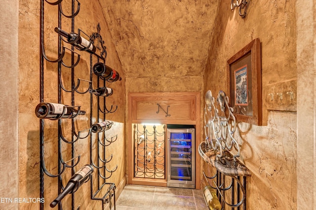 wine area with beverage cooler, lofted ceiling, and a bar