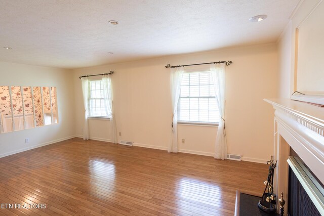 23 Windhaven Ln, Oak Ridge, TN 37830 - unfurnished living room featuring a fireplace with flush hearth, a wealth of natural light, visible vents, and light wood-style flooring