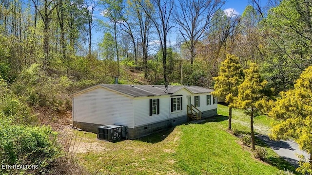 exterior space with a yard, central air condition unit, crawl space, and a wooded view