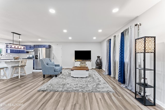 living room with light wood-style flooring, baseboards, and recessed lighting