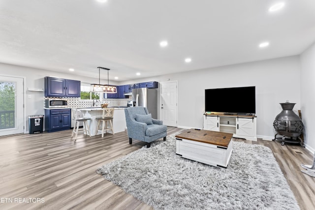 living room featuring baseboards, light wood-style floors, and recessed lighting